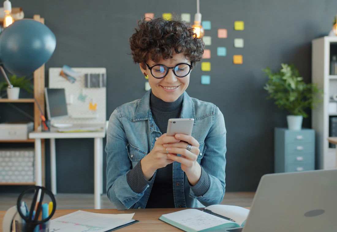 Colaboradora sorrindo ao consultar o contracheque pelo celular
